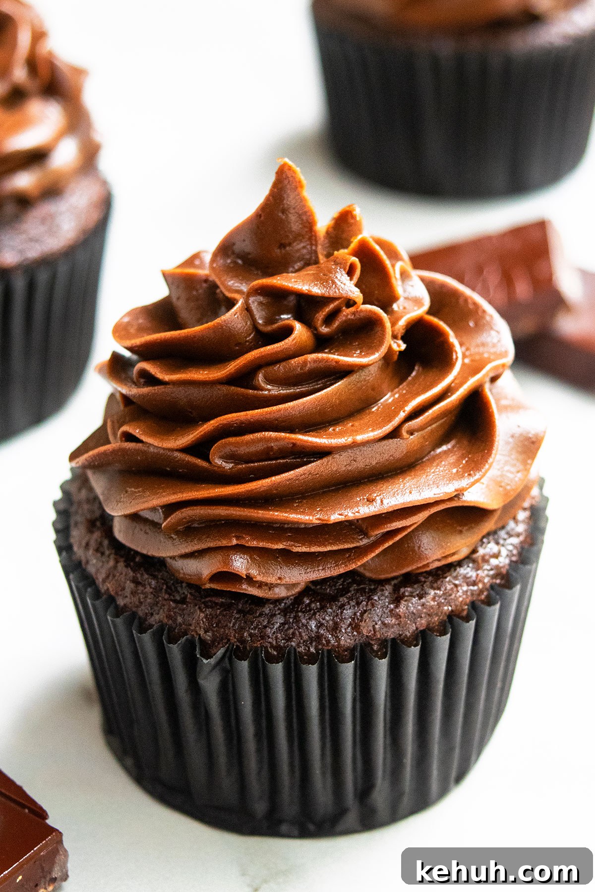 Frosted Soft And Moist Cocoa Cupcakes in Black Liner on White Marble Background.