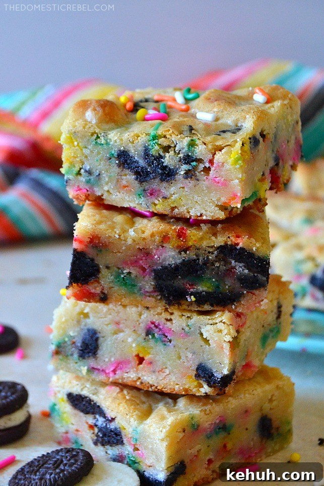 Cookies and Cream Cake-Batter Blondies: Decadent No-Fuss Treat 3 Four cookies & cream cake batter blondies stacked on white wood with oreo cookies