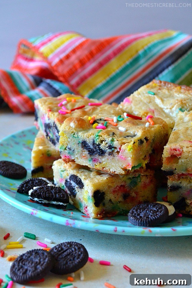 Cookies and Cream Cake-Batter Blondies: Decadent No-Fuss Treat 5 Blue plate filled with cookies & cream cake batter blondies with colorful fabric in backvground