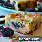 Cookies and Cream Cake-Batter Blondies: Decadent No-Fuss Treat 7 Cookie and cream cake batter blondie on white wood with oreos and sprinkels
