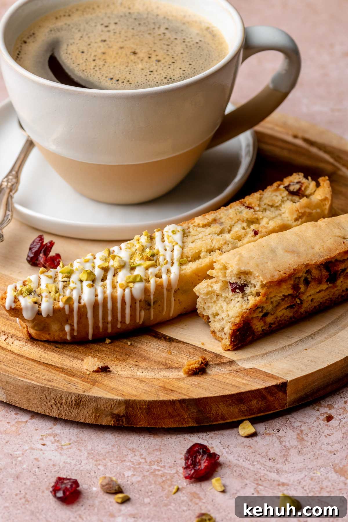 Pistachio biscotti pieces on a plate with a coffee cup.