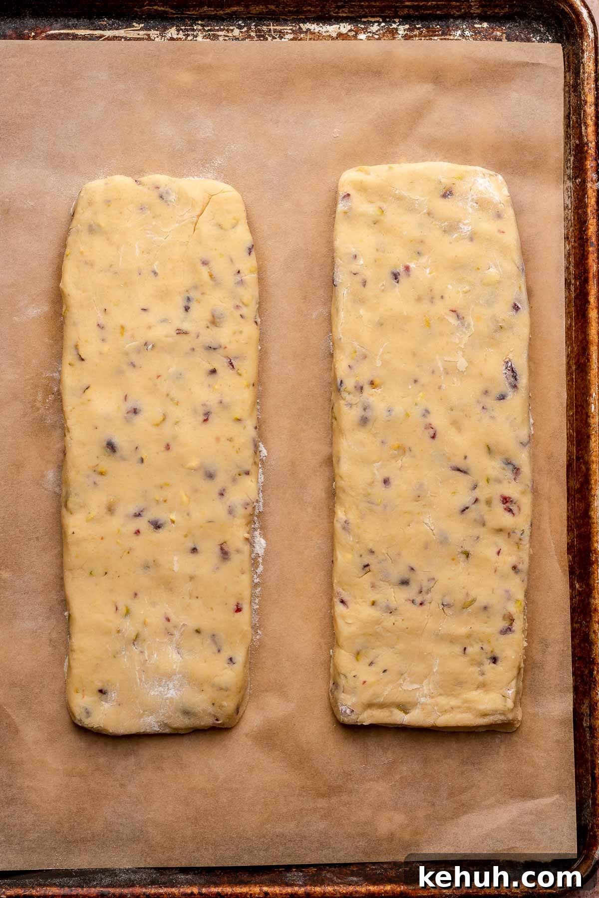 Two planks of pistachio biscotti dough formed on a sheet pan.