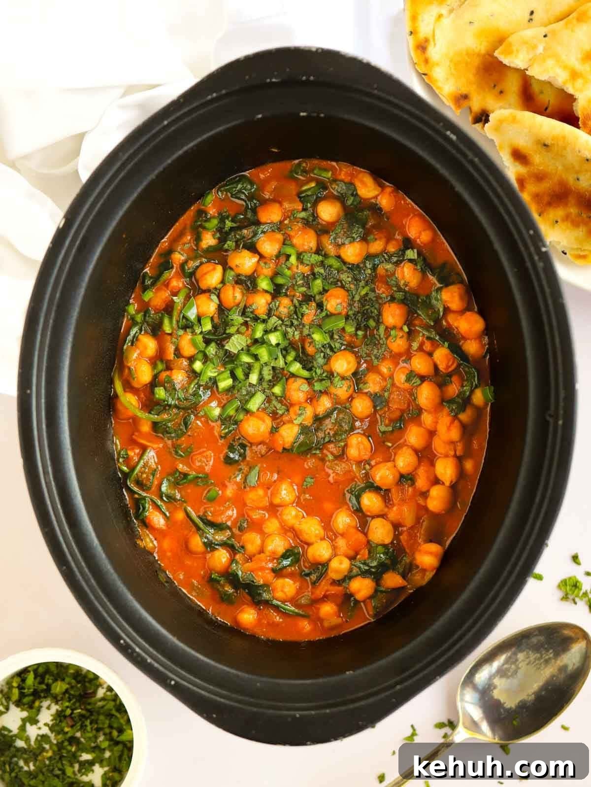 Slow cooker pan filled with chickpeas and spinach.