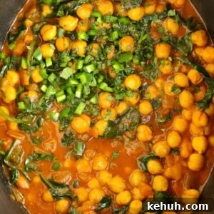 Chickpeas and spinach in a tomato, creamy sauce in the slow cooker for a vegetarian Chana Saag recipe.