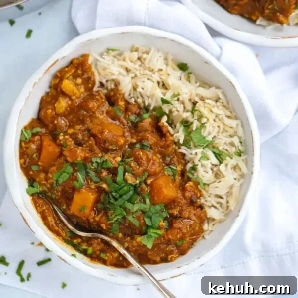 A bowl with butternut squash curry with rice and a fork ready to eat.