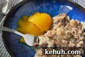 A serving of ground beef rice casserole and two scoops of pumpkin on a dark blue plate. A fork is inserted into the casserole from the left and a spoon in the upper left corner.