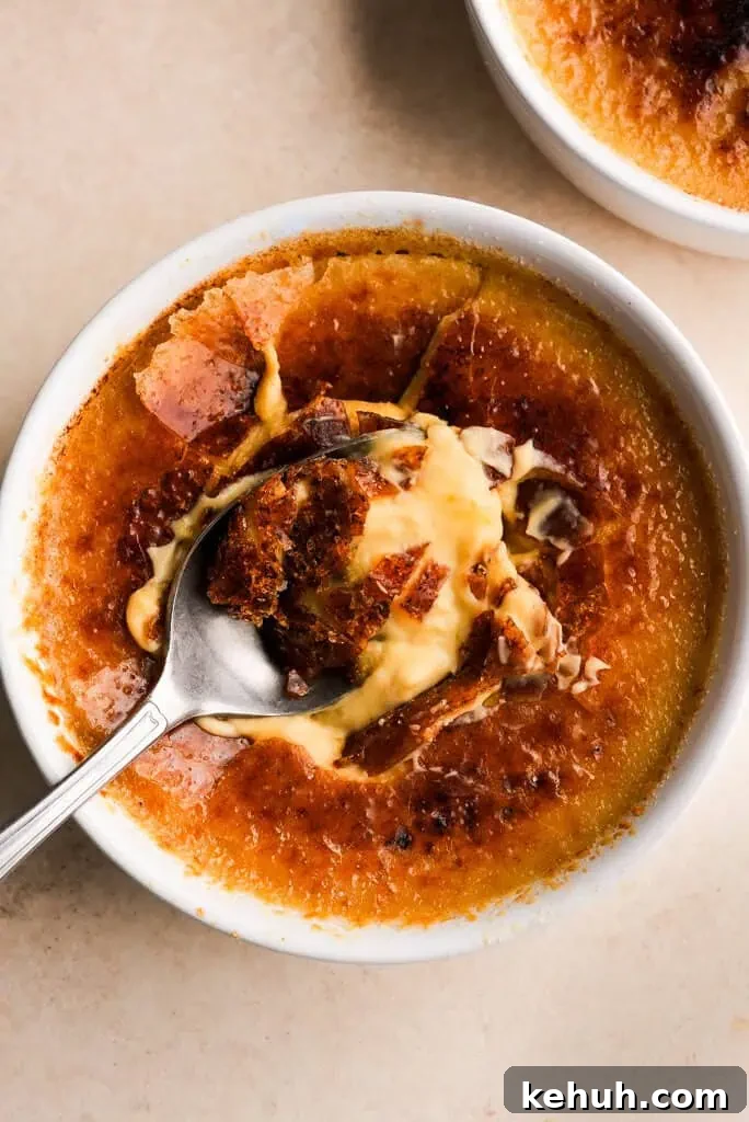 whisper of yum Pumpkin Creme Brulee Close-up of a pumpkin creme brulee with a spoon breaking through the caramelized sugar crust, revealing a creamy custard beneath.