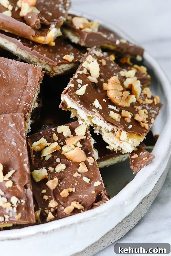 Classic Cracker Toffee Recipe with Crunchy Caramel Topping 2 Stack of cracker toffee pieces topped with chocolate, salt and chopped nuts.