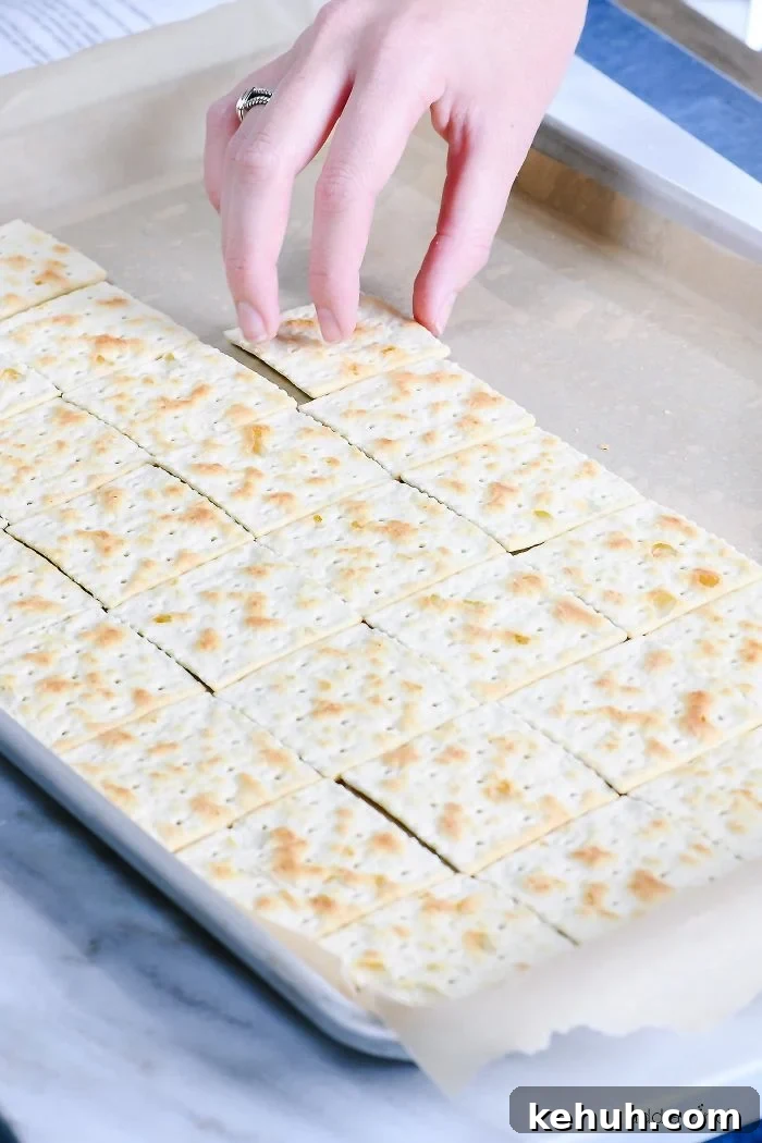 Classic Cracker Toffee Recipe with Crunchy Caramel Topping 3 Laying saltine crackers on a baking sheet lined in parchment paper.