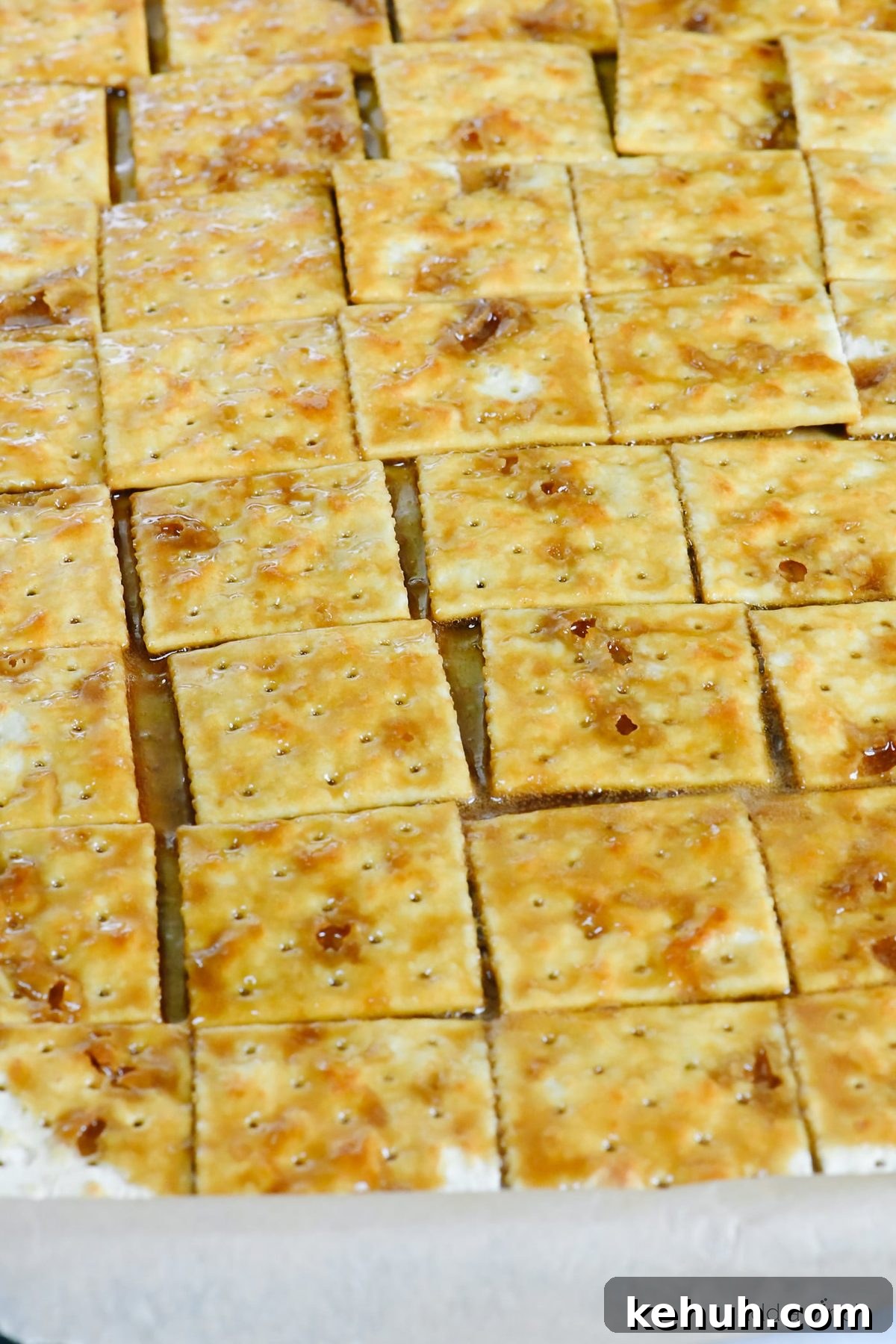 Classic Cracker Toffee Recipe with Crunchy Caramel Topping 5 Saltine crackers on a baking sheet have caramel poured over them.