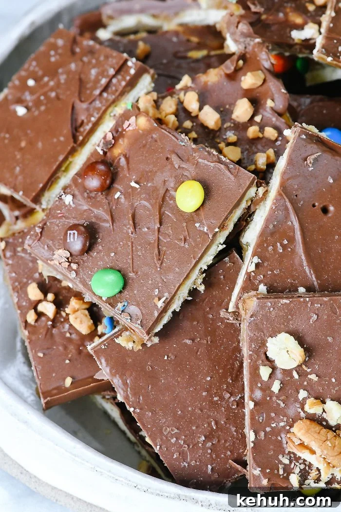 Classic Cracker Toffee Recipe with Crunchy Caramel Topping 9 Cracker toffee is covered in chocolate, toffee bits, mini chocolate candies and nuts, all served on a tray.