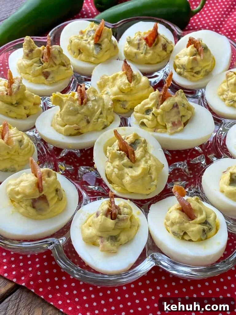 Bacon Jalapeño Deviled Eggs Recipe – Spicy Stuffed Egg Bites 3 Generously filled keto eggs with bacon next to fresh jalapenos on a red napkin