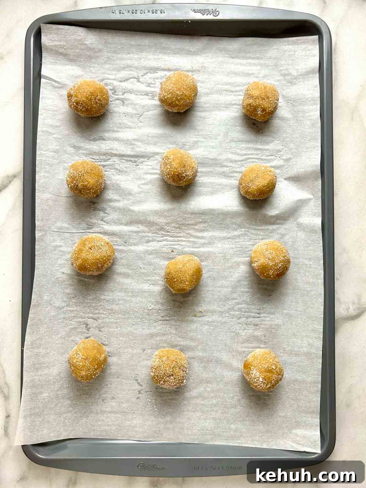 Classic Peanut Butter Blossom Cookies: Soft Chocolate Kiss Treats 8 dough shaped into balls and rolled in sugar; arranged on parchment lined baking sheet.