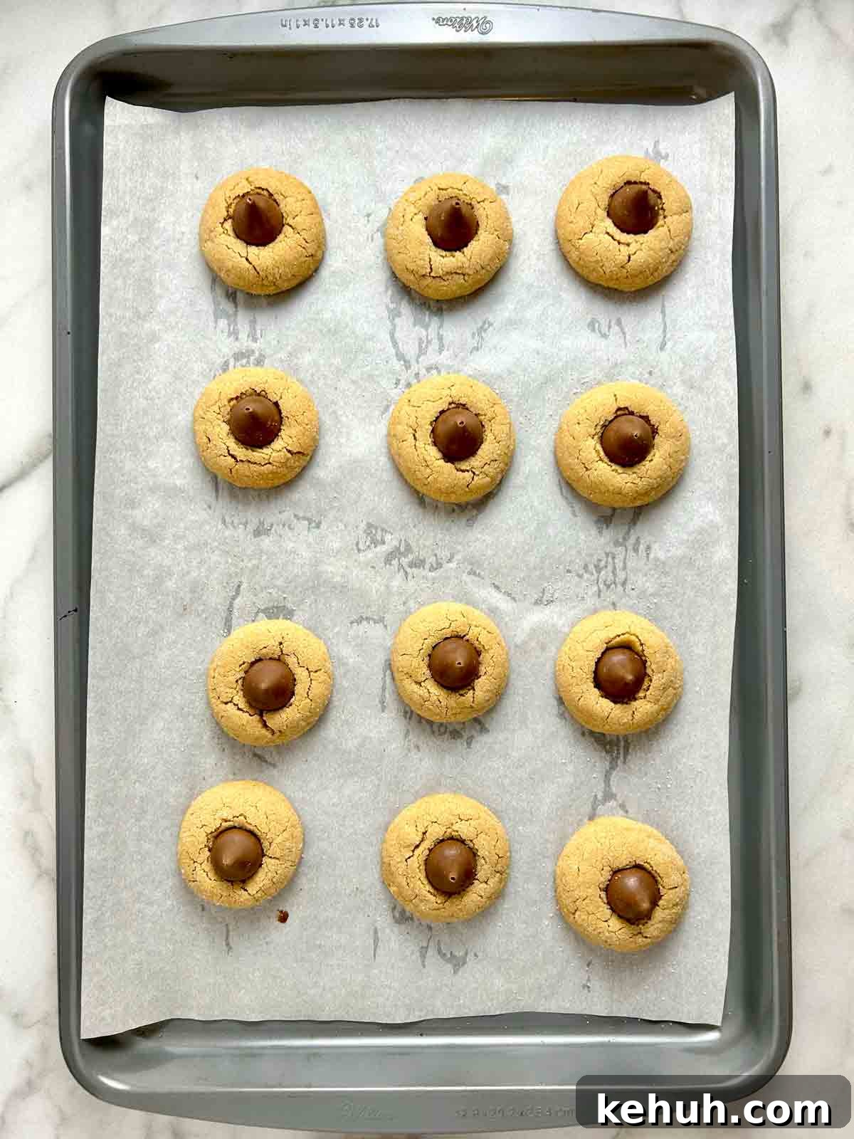 Classic Peanut Butter Blossom Cookies: Soft Chocolate Kiss Treats 10 overhead shot of Hershey's Kisses pressed onto tops of peanut butter cookies.