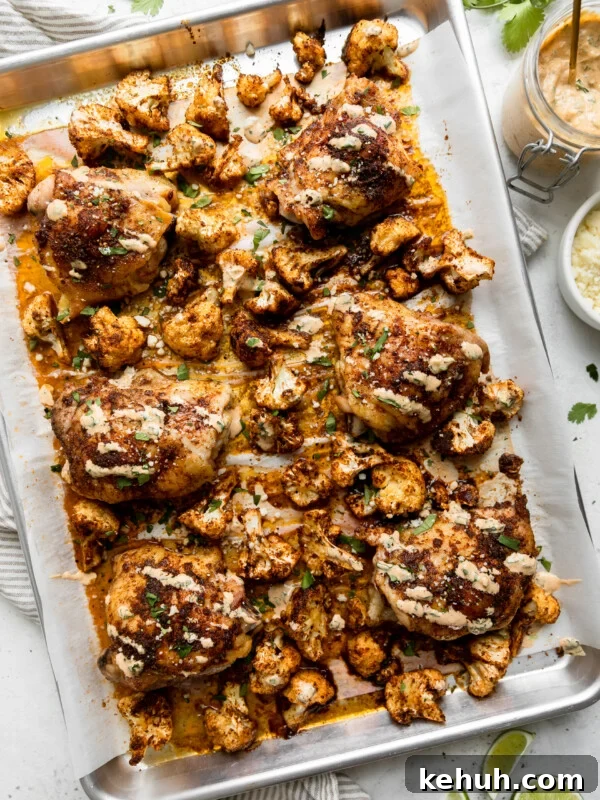 a silver sheet pan with roasted cauliflower and chicken thighs