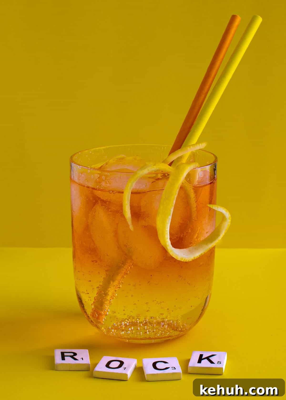 Classic Rock Shandy Recipe: Refreshing Lemon Beer Cocktail 2 A medium glass of Rock shandy on a yellow background with an orange and yellow straw.