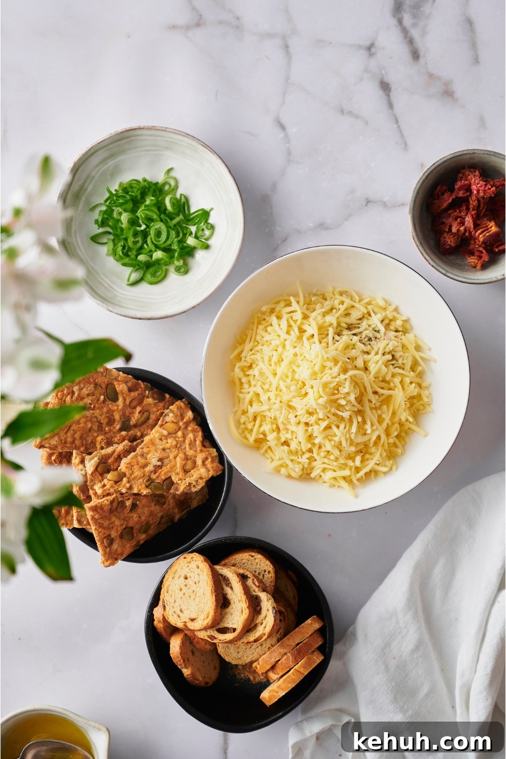 Ranch Bacon Cheddar Crack Dip Recipe for Parties 4 Bowl of shredded cheese, crackers, bread slices, bacon bits, and green onion.