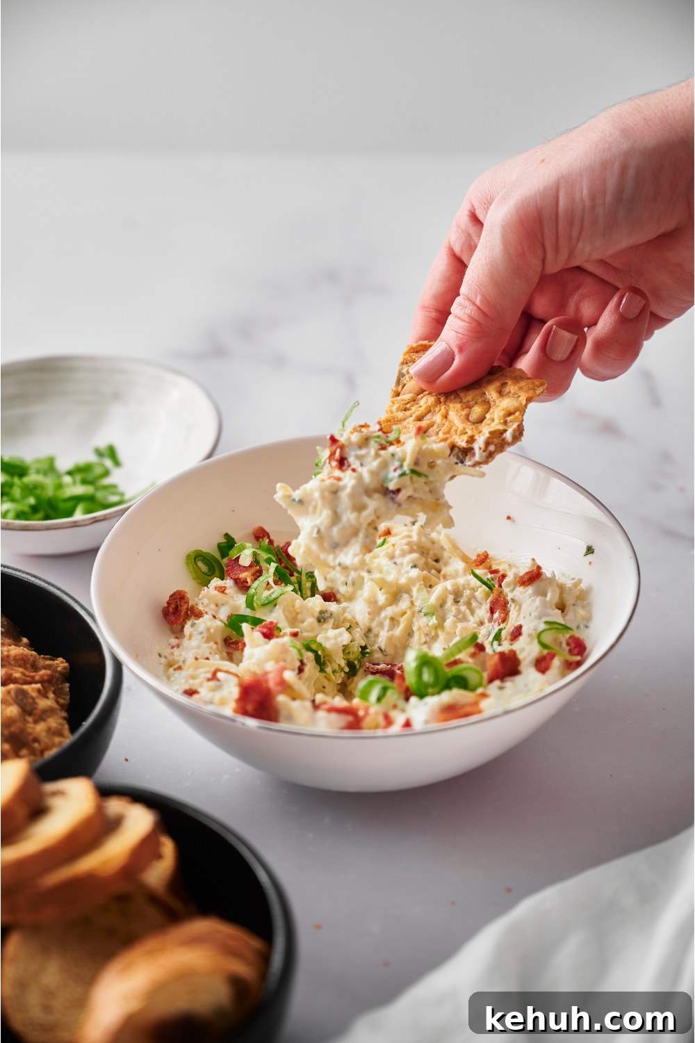 Ranch Bacon Cheddar Crack Dip Recipe for Parties 7 Hand scooping crack dip with a tortilla chip.