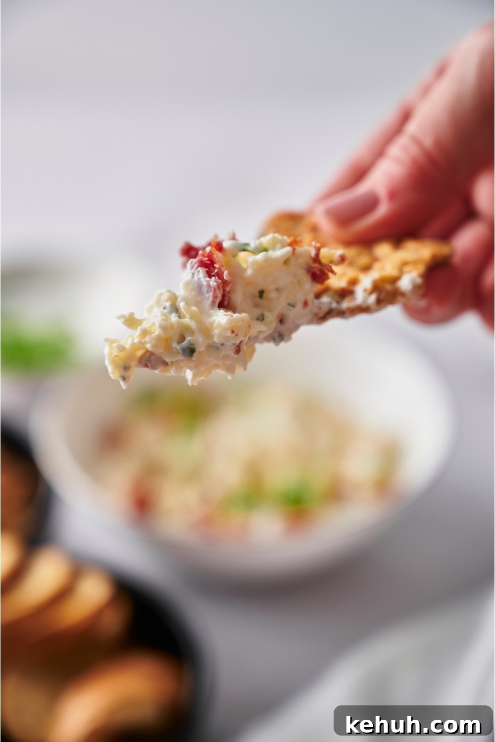 Ranch Bacon Cheddar Crack Dip Recipe for Parties 8 Hand holding a tortilla chip with crack dip.