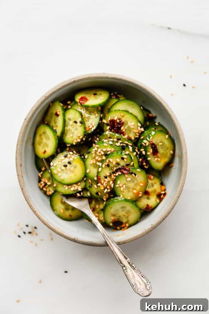 Quick Asian Cucumber Salad Ready in 10 Minutes 3 sliced cucumbers in a bowl topped with asian dressing and sesame seeds