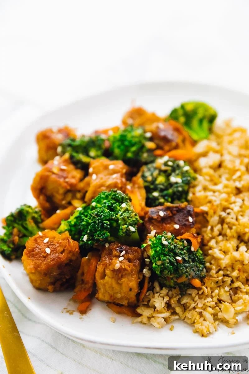 Close up of tempeh stir fry on a white plate. 