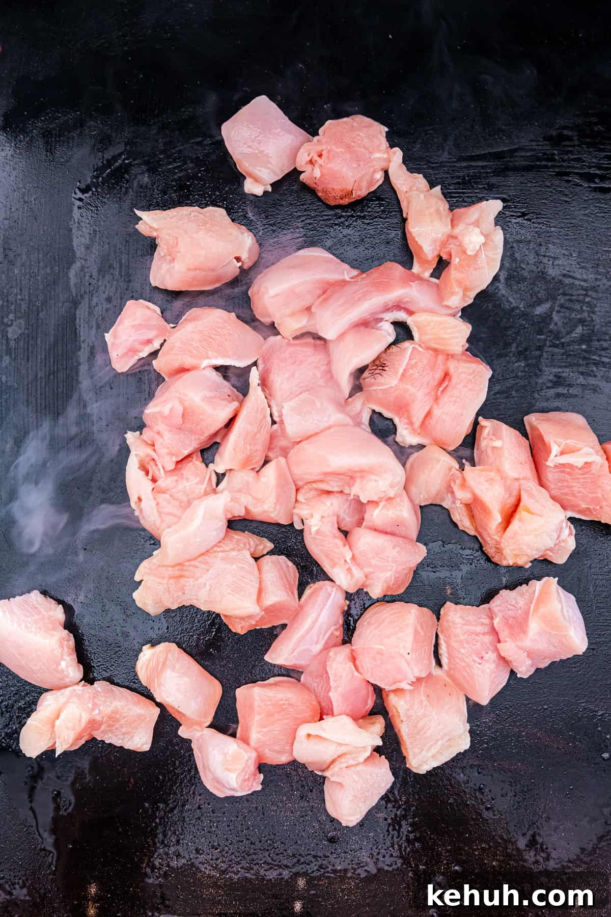 Cubed chicken on griddle seasoned with olive oil for Blackstone Teriyaki Chicken recipe