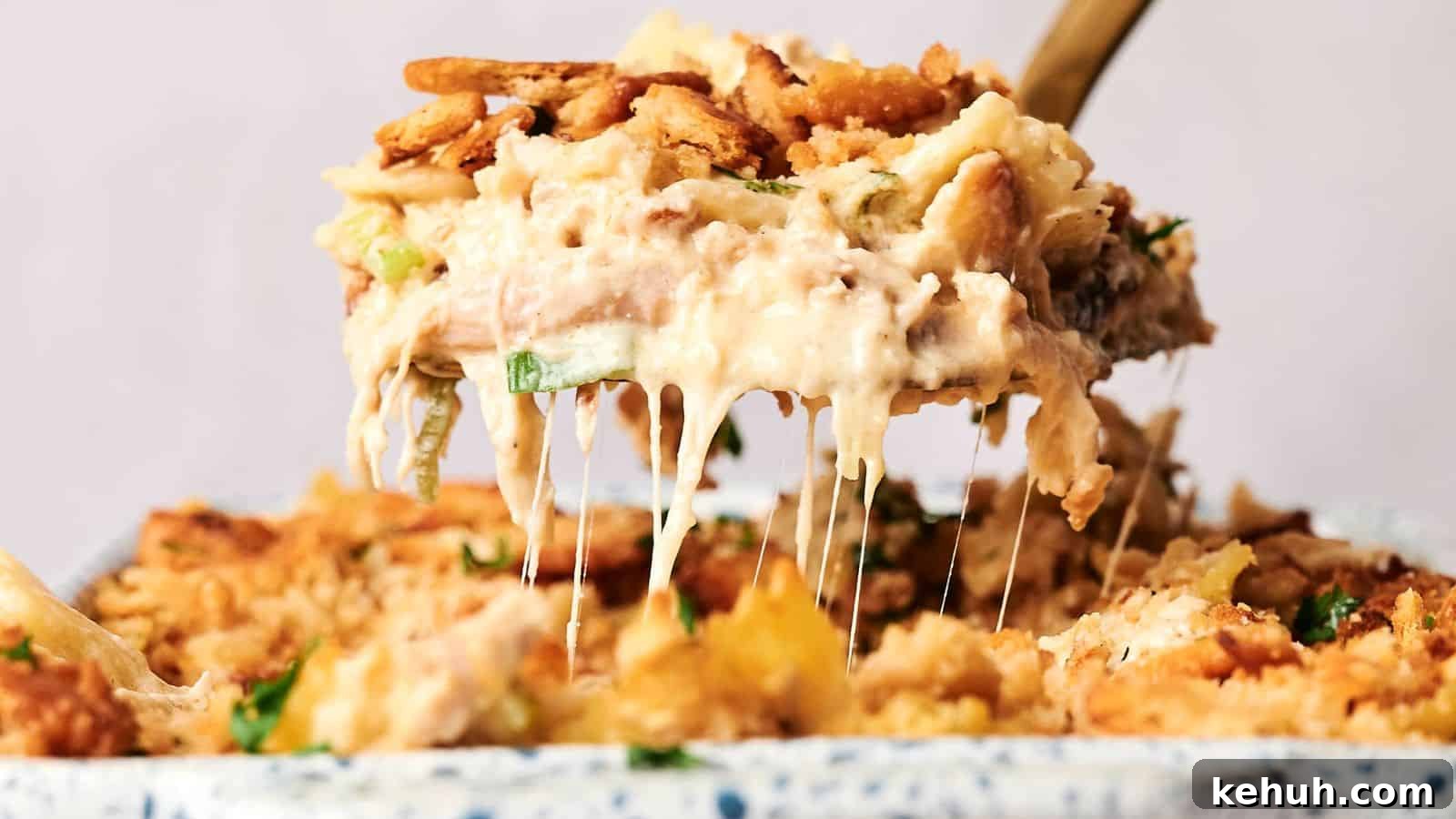 31 Homemade Thanksgiving Sides That Outshine Store-Bought 17 A serving spoon lifts a portion of creamy, baked casserole with a crunchy topping, revealing melted cheese.