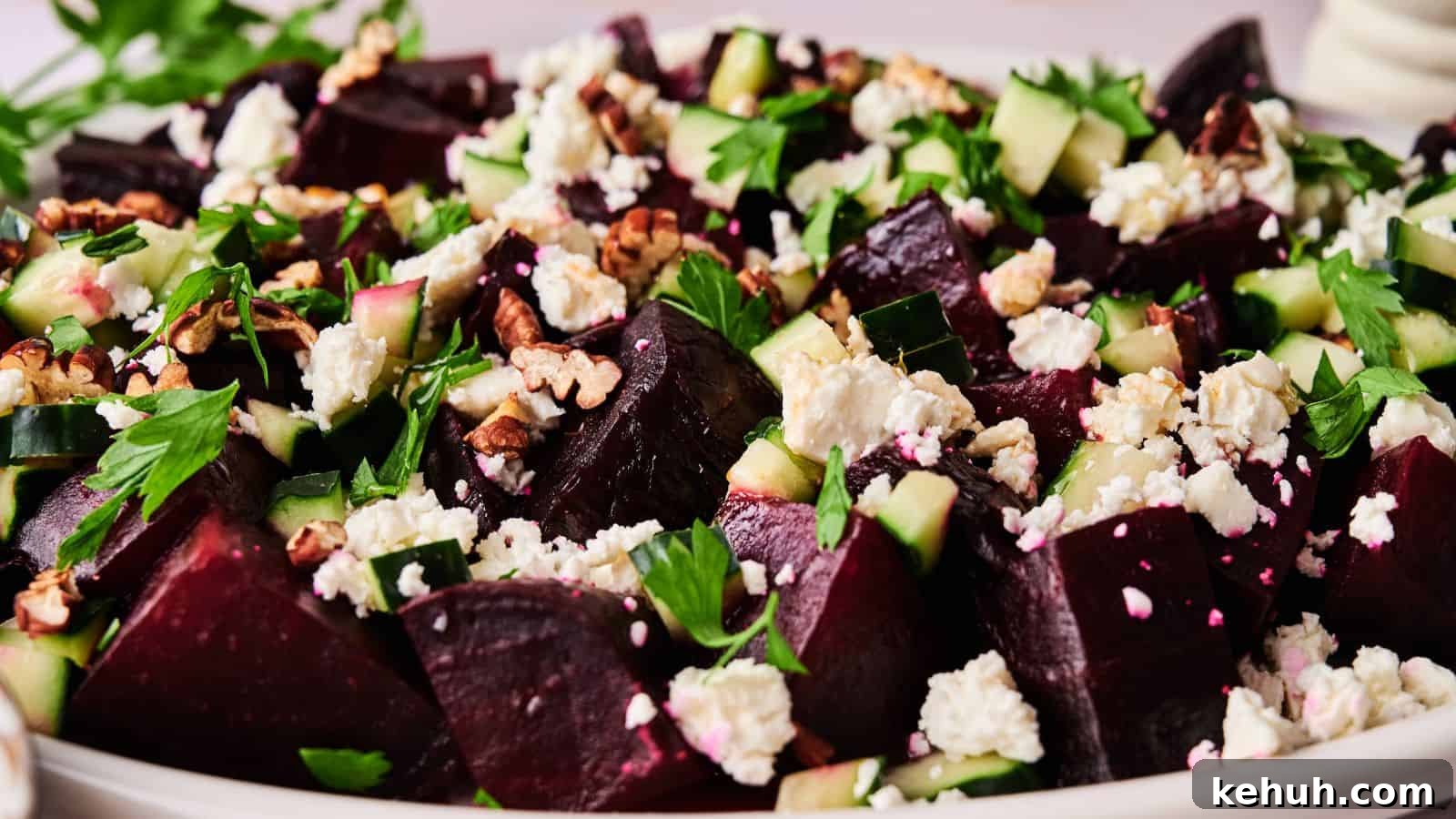 31 Homemade Thanksgiving Sides That Outshine Store-Bought 3 A close-up of a salad featuring chopped beets, cucumber, feta cheese, walnuts, and fresh herbs on a white plate.