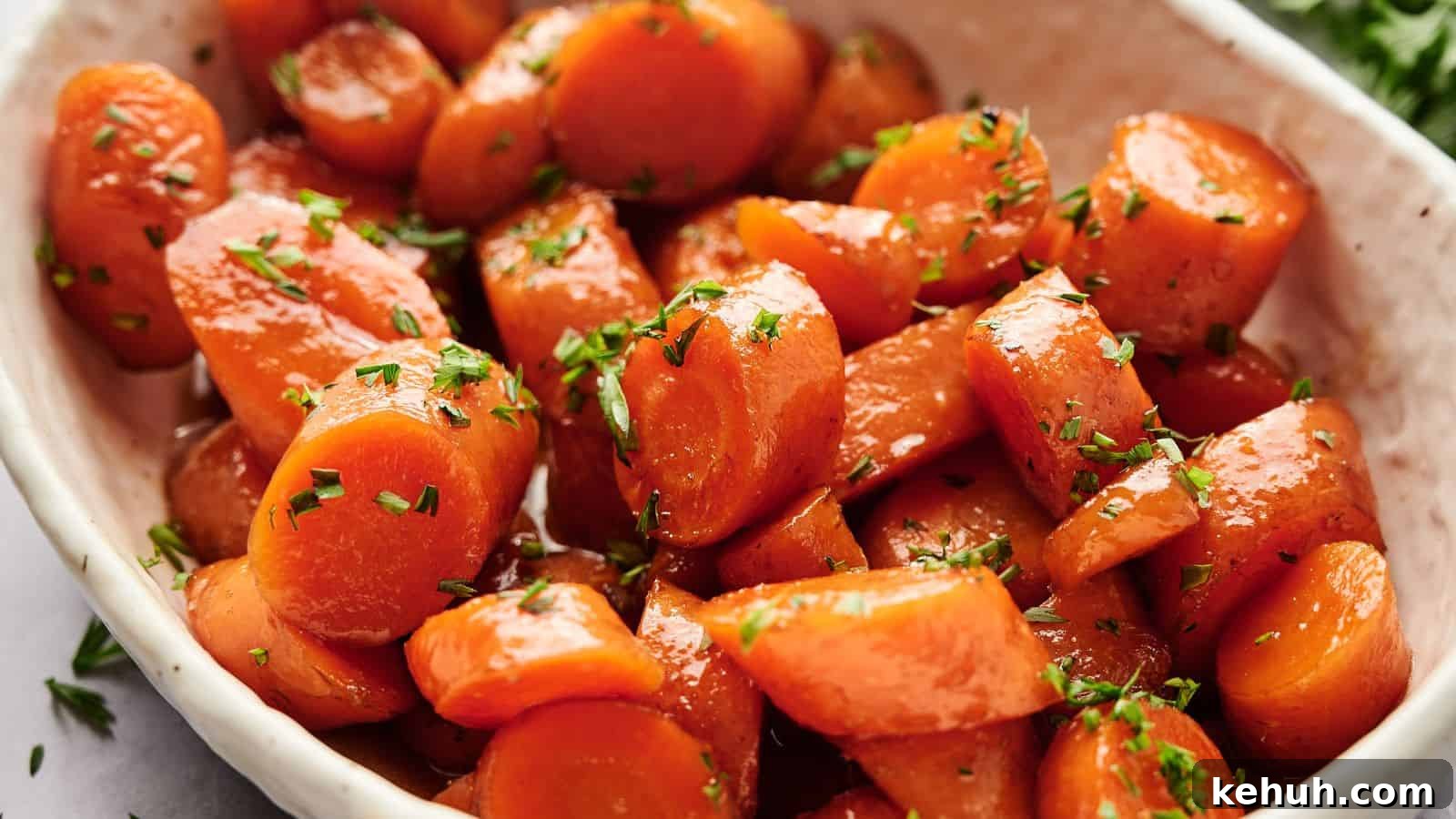 31 Homemade Thanksgiving Sides That Outshine Store-Bought 10 Close-up of a dish featuring glazed carrots garnished with chopped herbs, served in a white bowl.