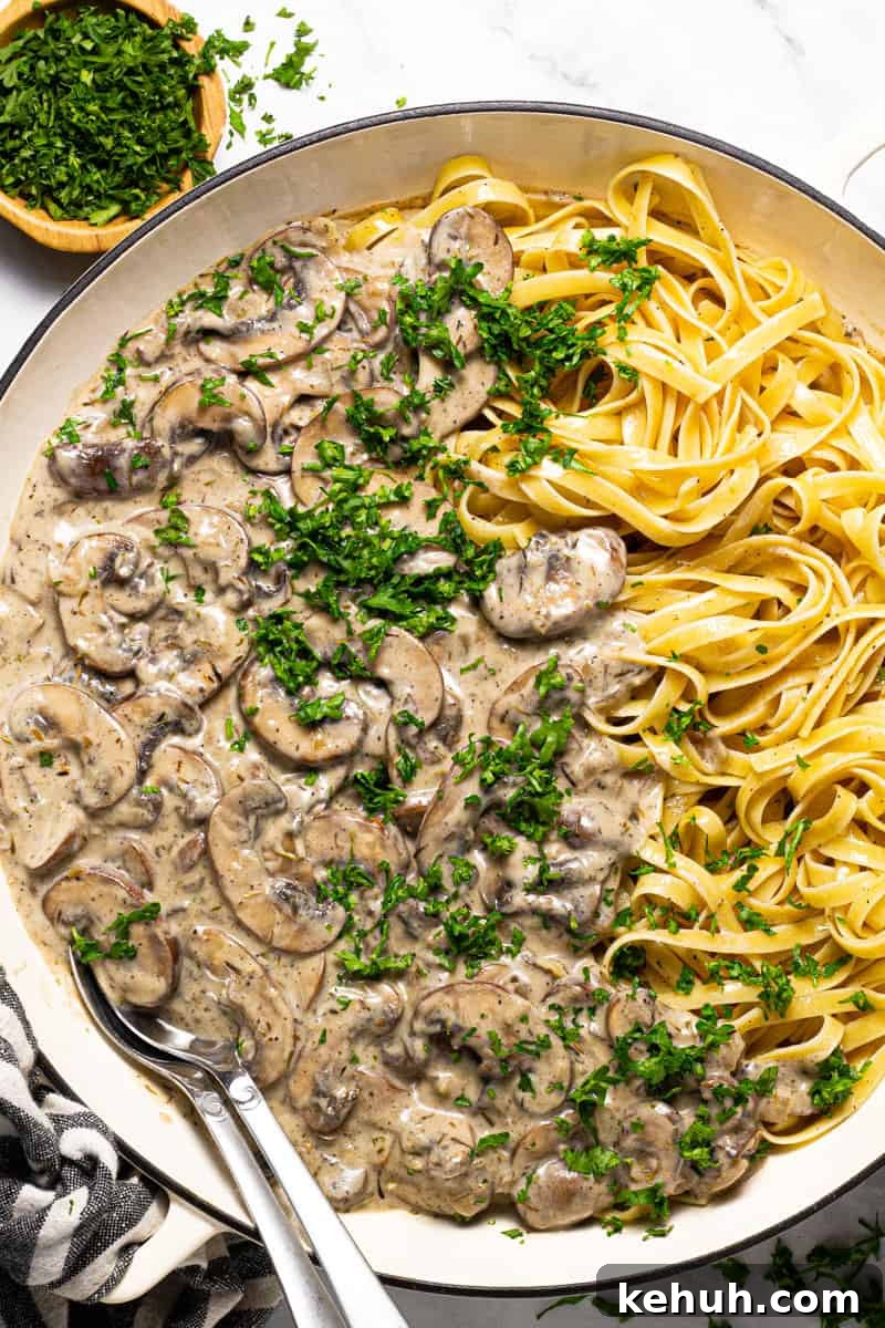 Vegan Mushroom Stroganoff Without Cashew Cream or Roux 2 Large white pan filled with vegan mushroom stroganoff garnished with fresh chopped parsley