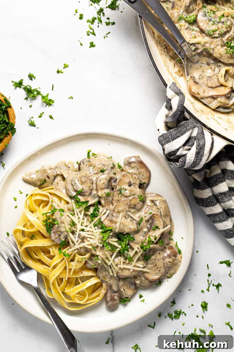 Vegan Mushroom Stroganoff Without Cashew Cream or Roux 10 White plate with vegan stroganoff and fettuccine noodles garnished with parsley