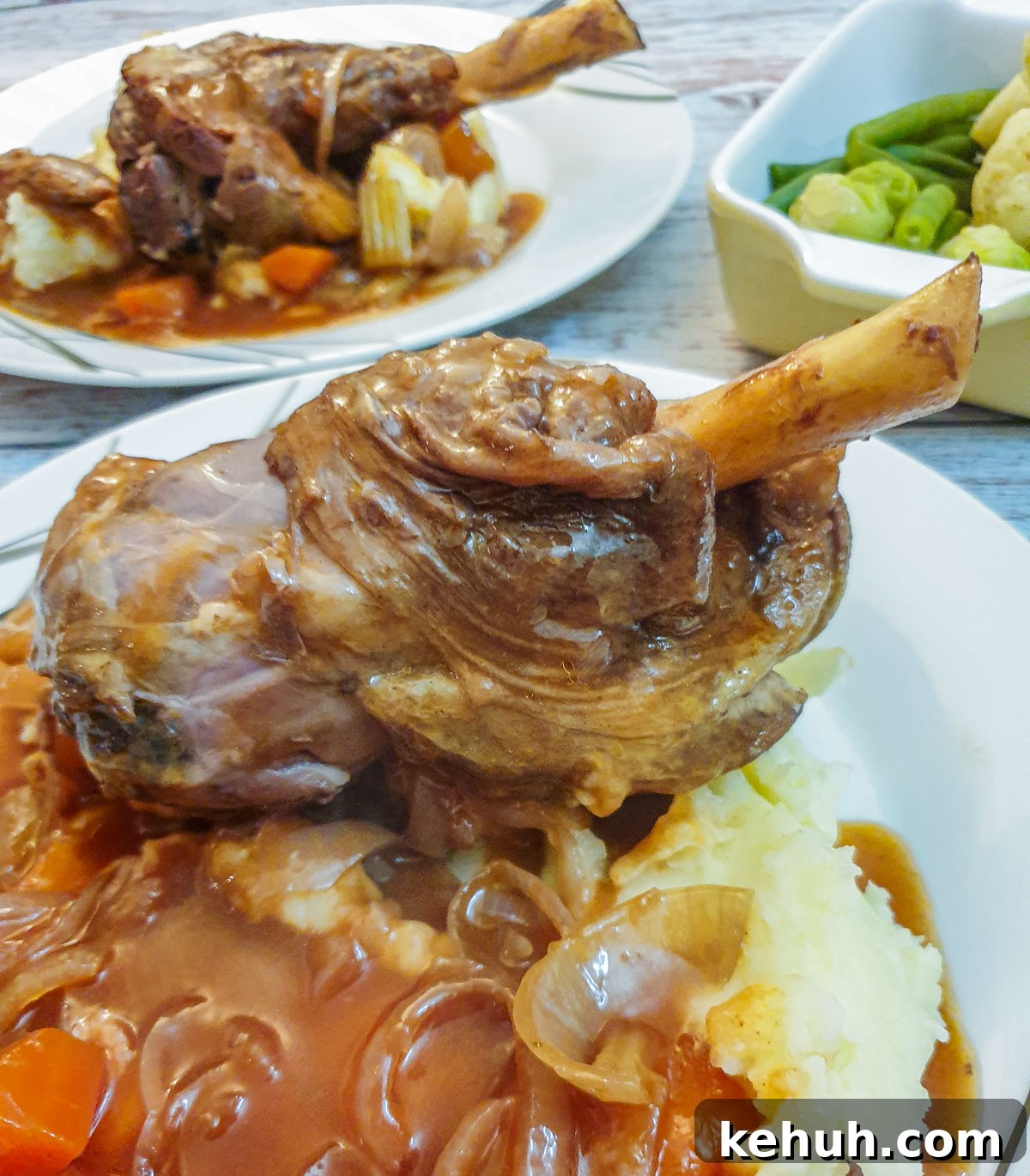 Closeup of a lamb shank on a bed of mashed potatoes.