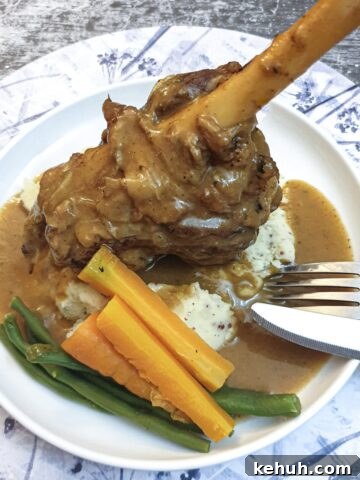 A minted lamb shank on a bed of mustard mashed potatoes.