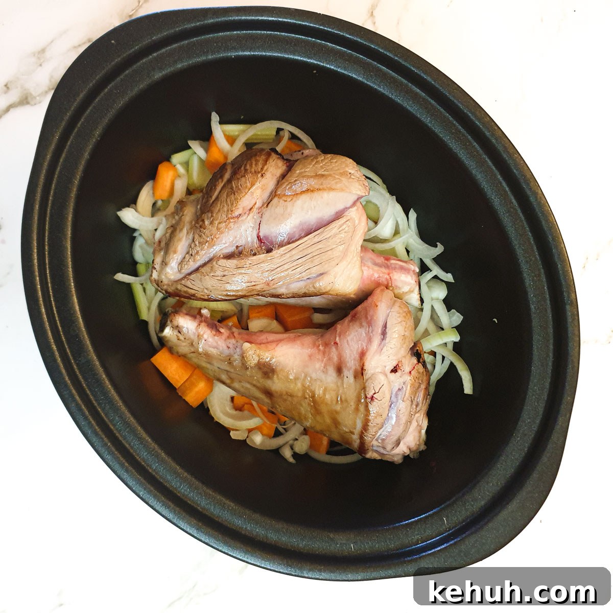 Lamb shanks on top of the vegetables in a slow-cooker.