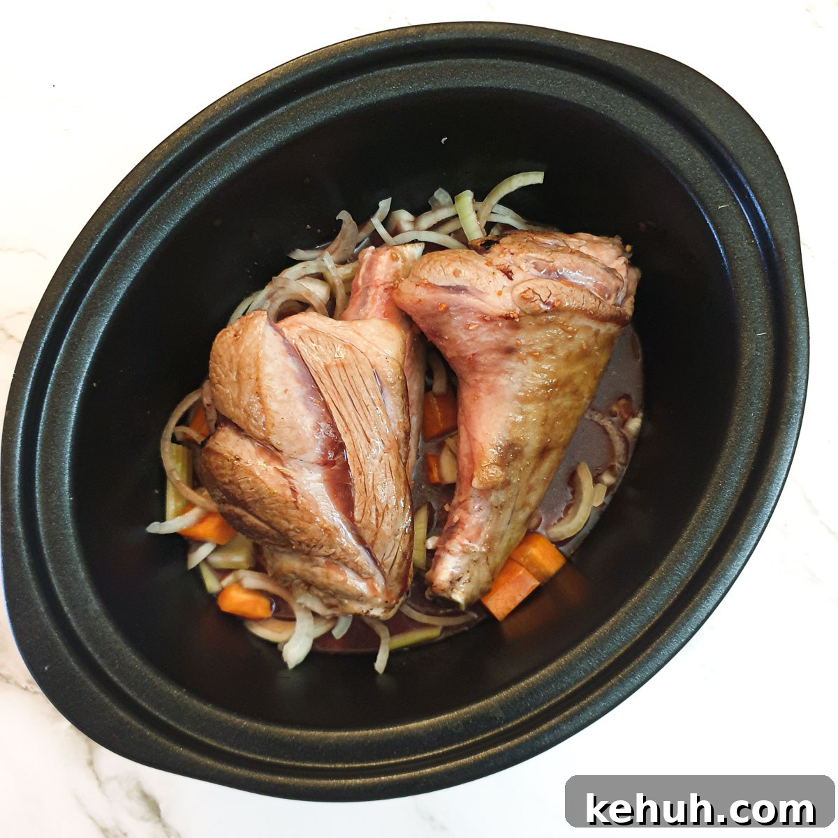 Lamb shanks and vegetables in a slow-cooker covered with stock.