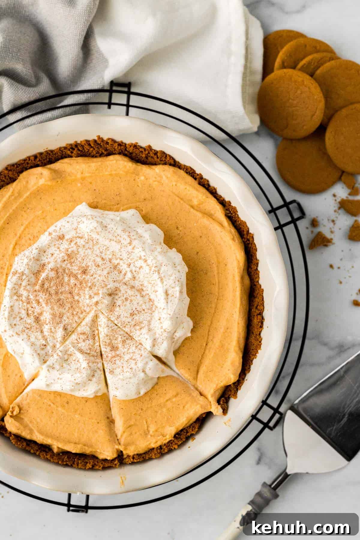 Pumpkin Mousse Pie with Gingersnap Crust — Creamy Fall Dessert 2 pumpkin mousse pie in white pie dish on black cooling rack with pie server and gingersnap cookies