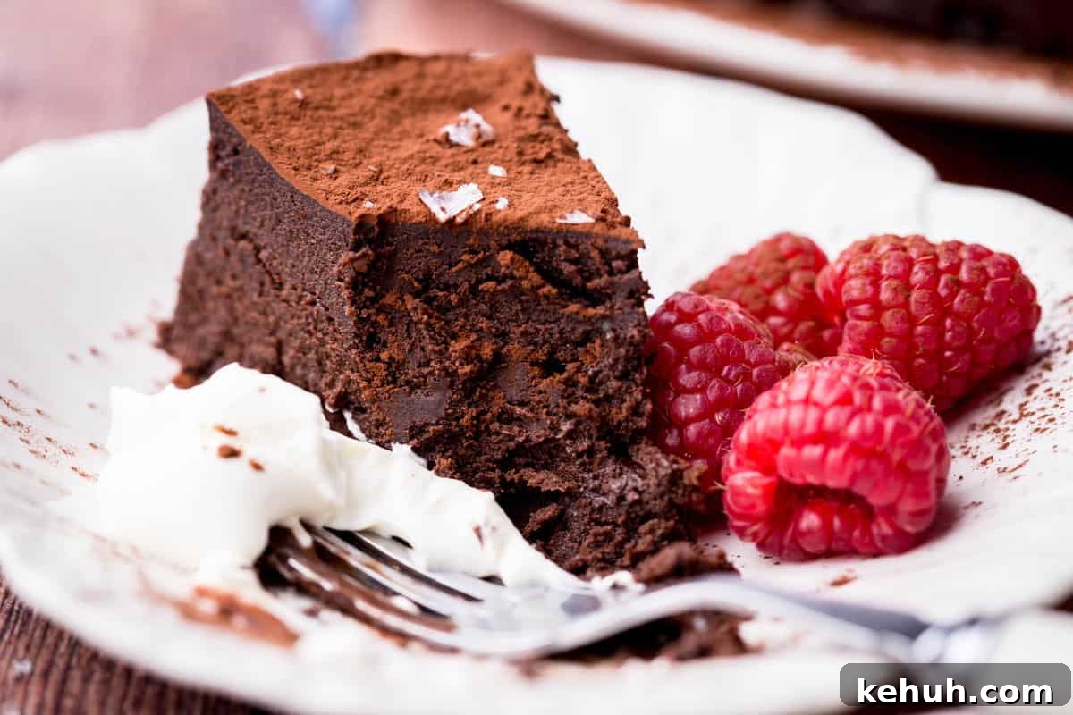 Olive Oil Chocolate Cake (Flourless, Rich & Decadent) 16 Flourless Olive Oil Chocolate Cake showing fudgy inside next to whipped cream and raspberries.