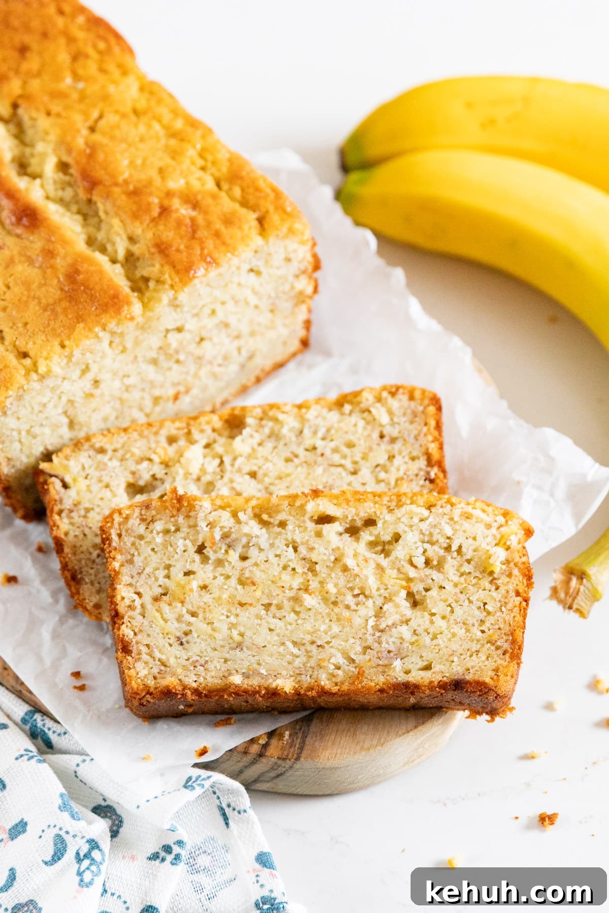 Moist Buttermilk Banana Bread with Brown Sugar Glaze 2 Two slices of banana bread next to the loaf with a banana on the side.