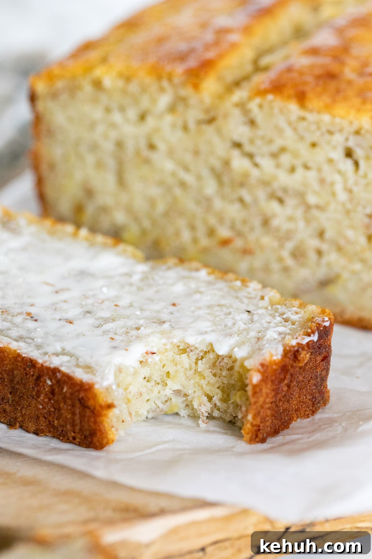 Moist Buttermilk Banana Bread with Brown Sugar Glaze 8 A close up image of a slice of banana bread with butter and a bite taken out of it.