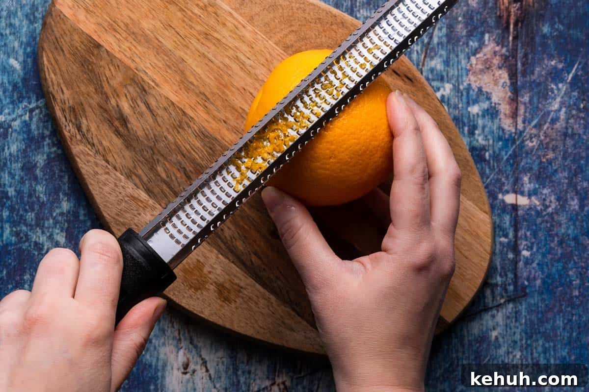 microplane zesting an orange on wooden cutting board