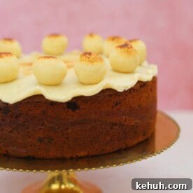 Gluten-Free Simnel Cake Recipe: Traditional Easter Fruit Cake 11 A gluten free simnel cake on a gold cake stand with a pink backdrop.