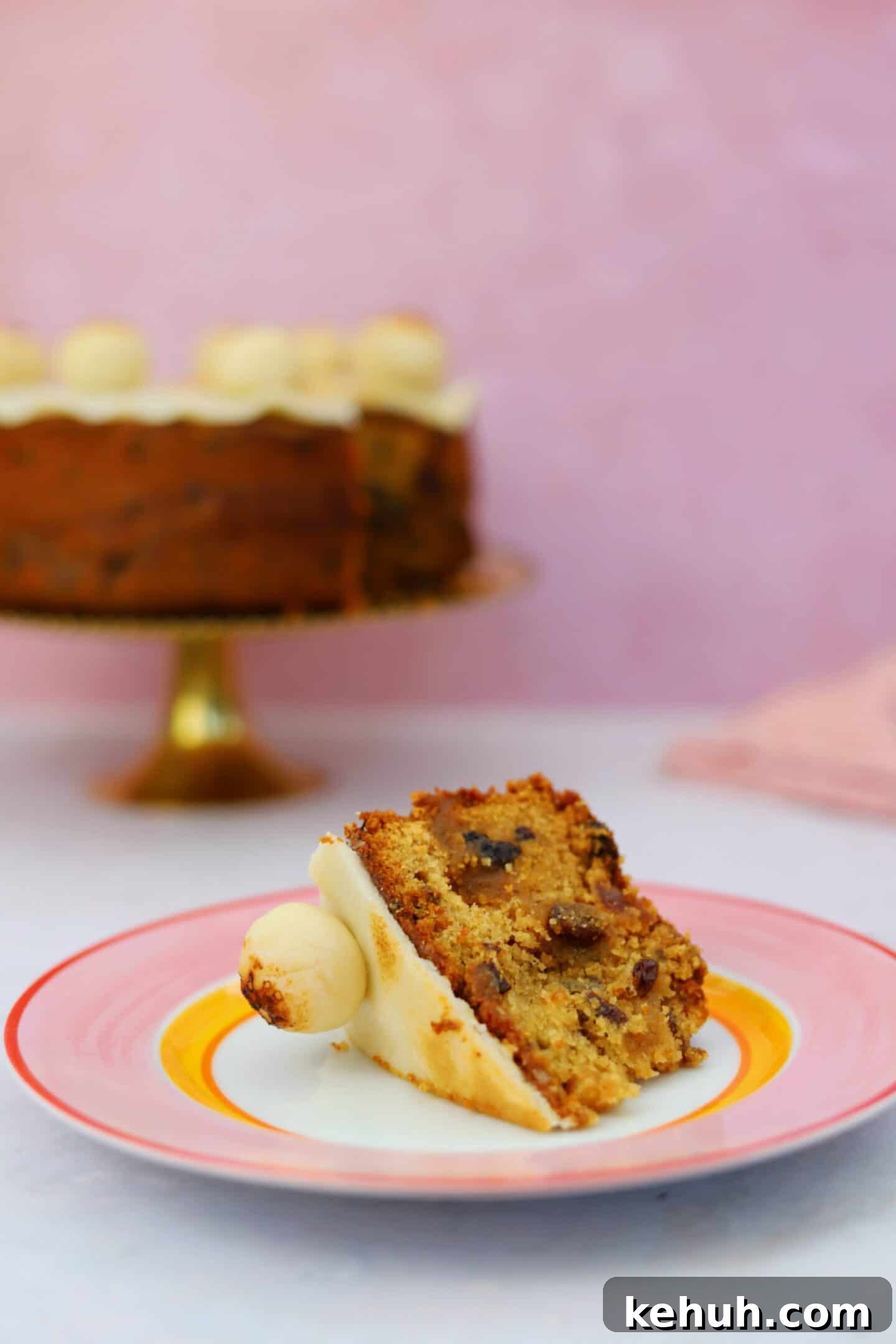 Gluten-Free Simnel Cake Recipe: Traditional Easter Fruit Cake 3 A slice of gluten free simnel cake on a plate with the rest of the cake in the background.