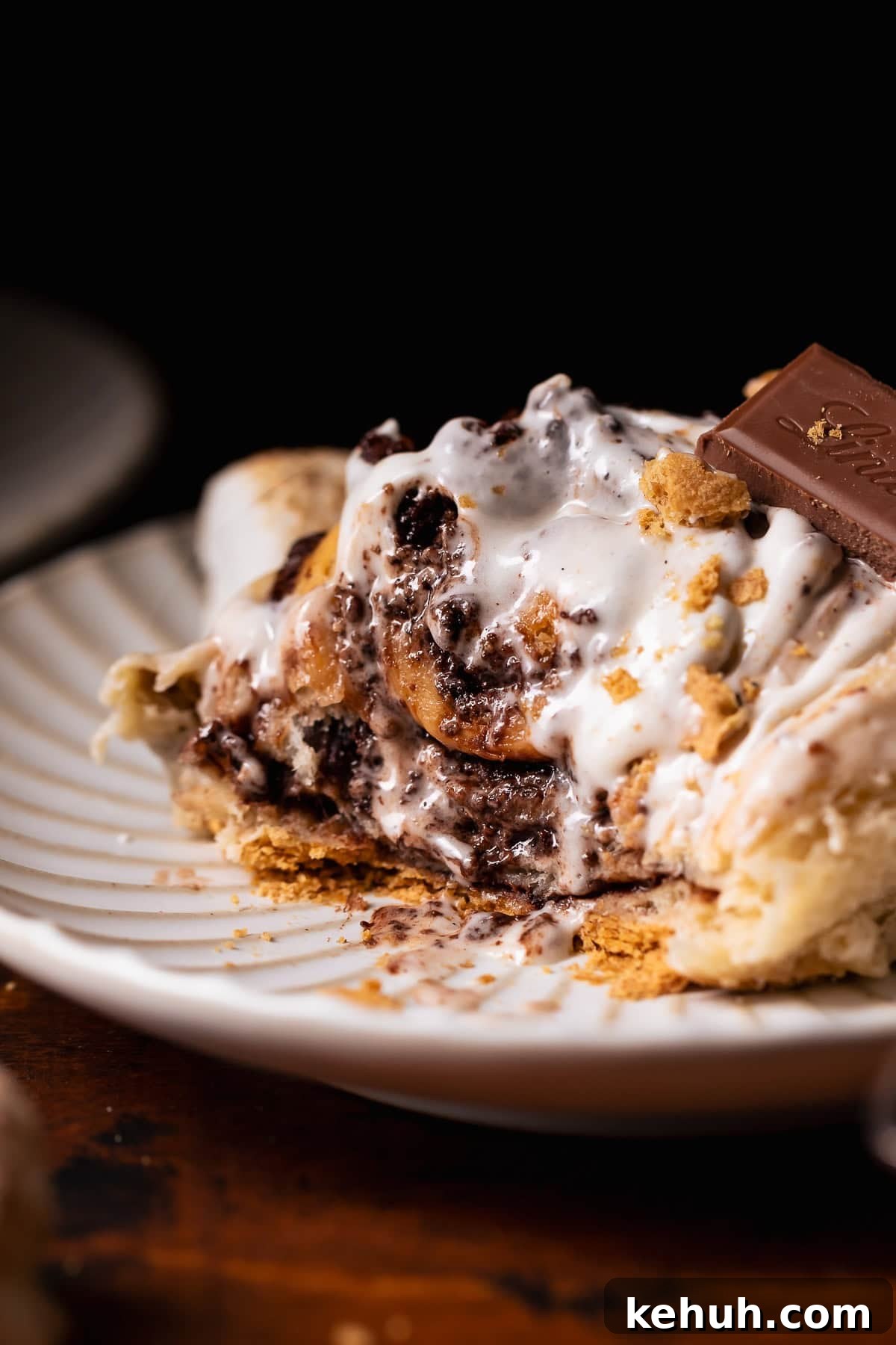 A smores roll on a white plate with bites missing to show the gooey texture.