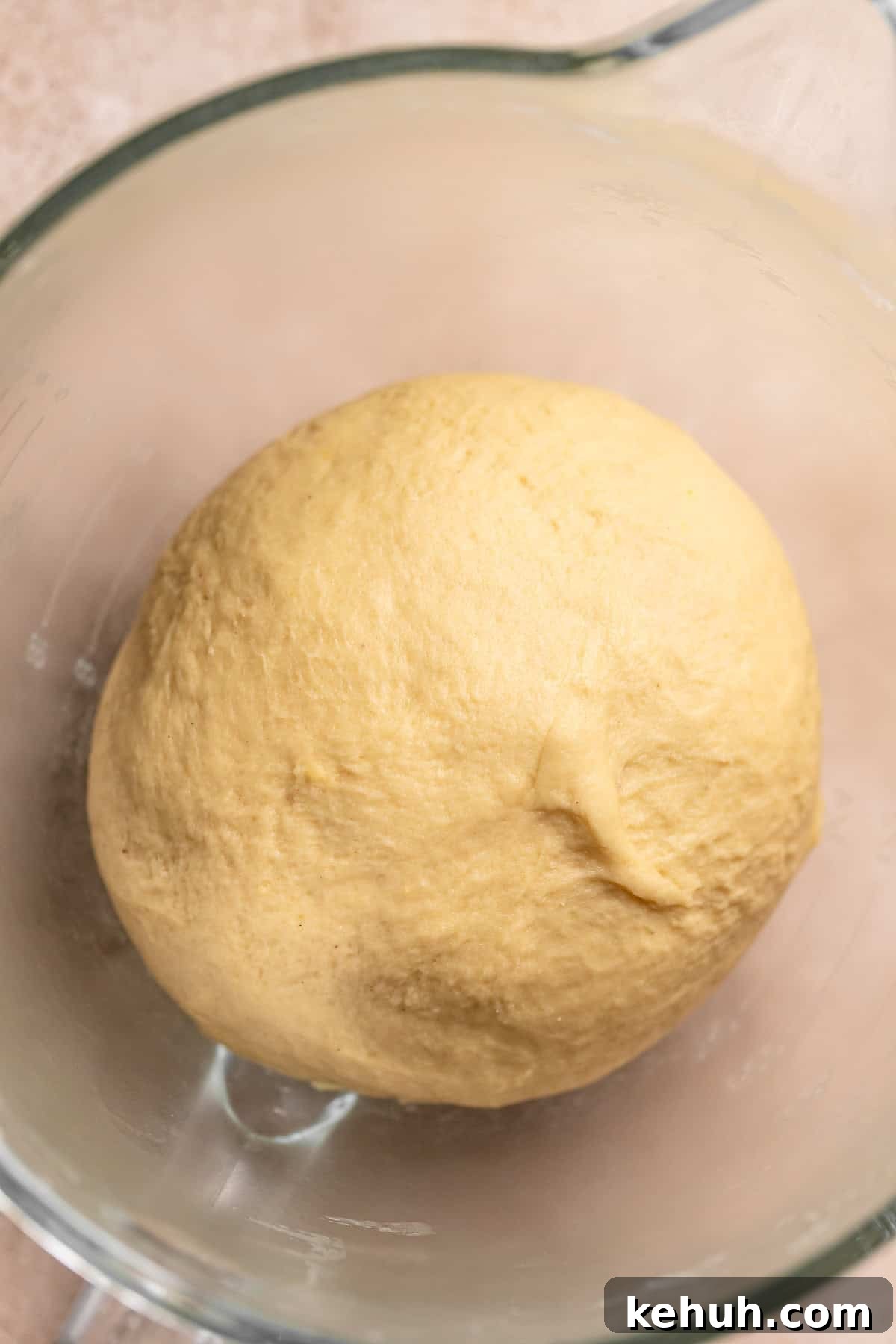 A formed round dough ball in a glass mixing bowl.