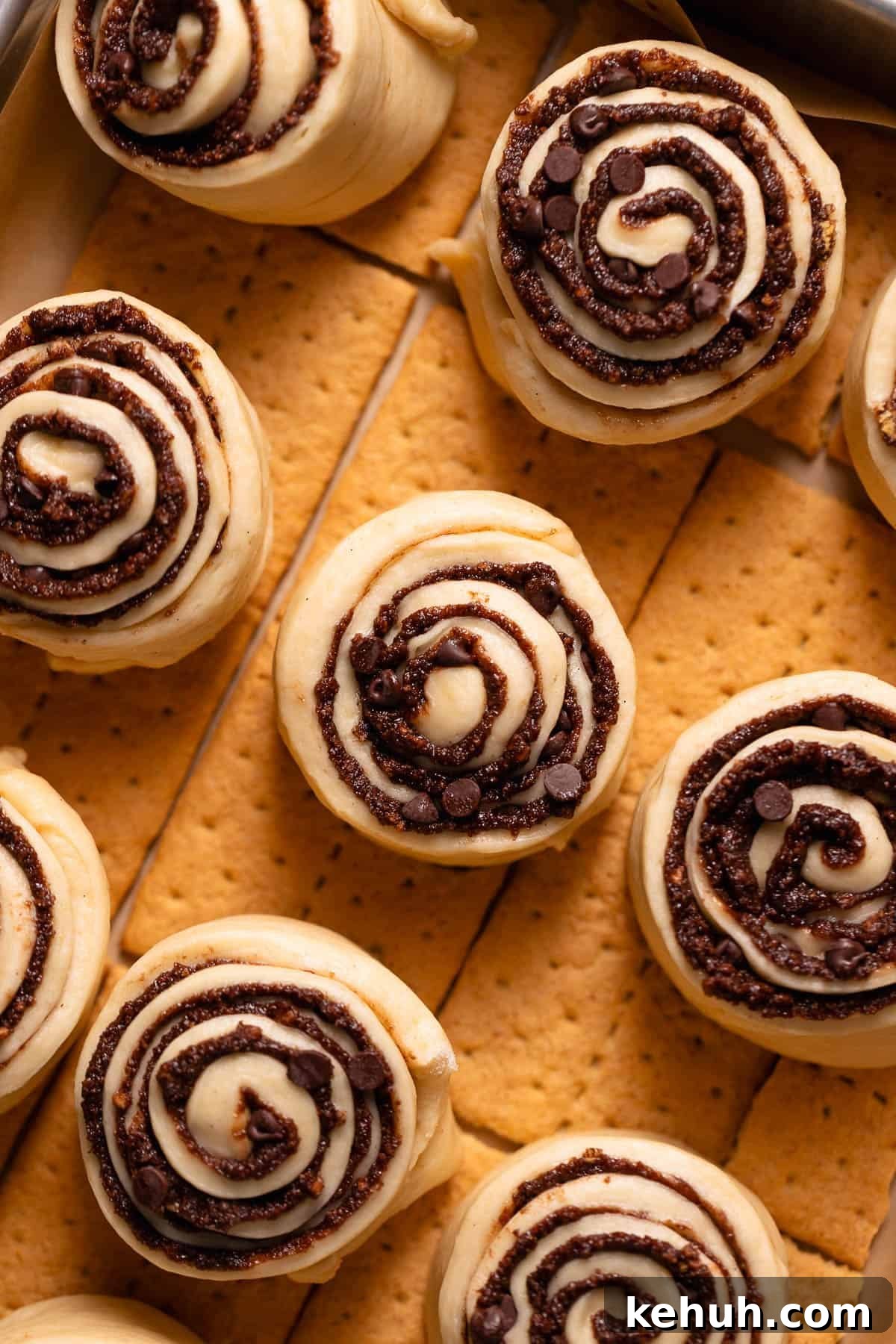 S'mores cinnamon rolls in a baking pan sitting on top of graham cracker sheets.