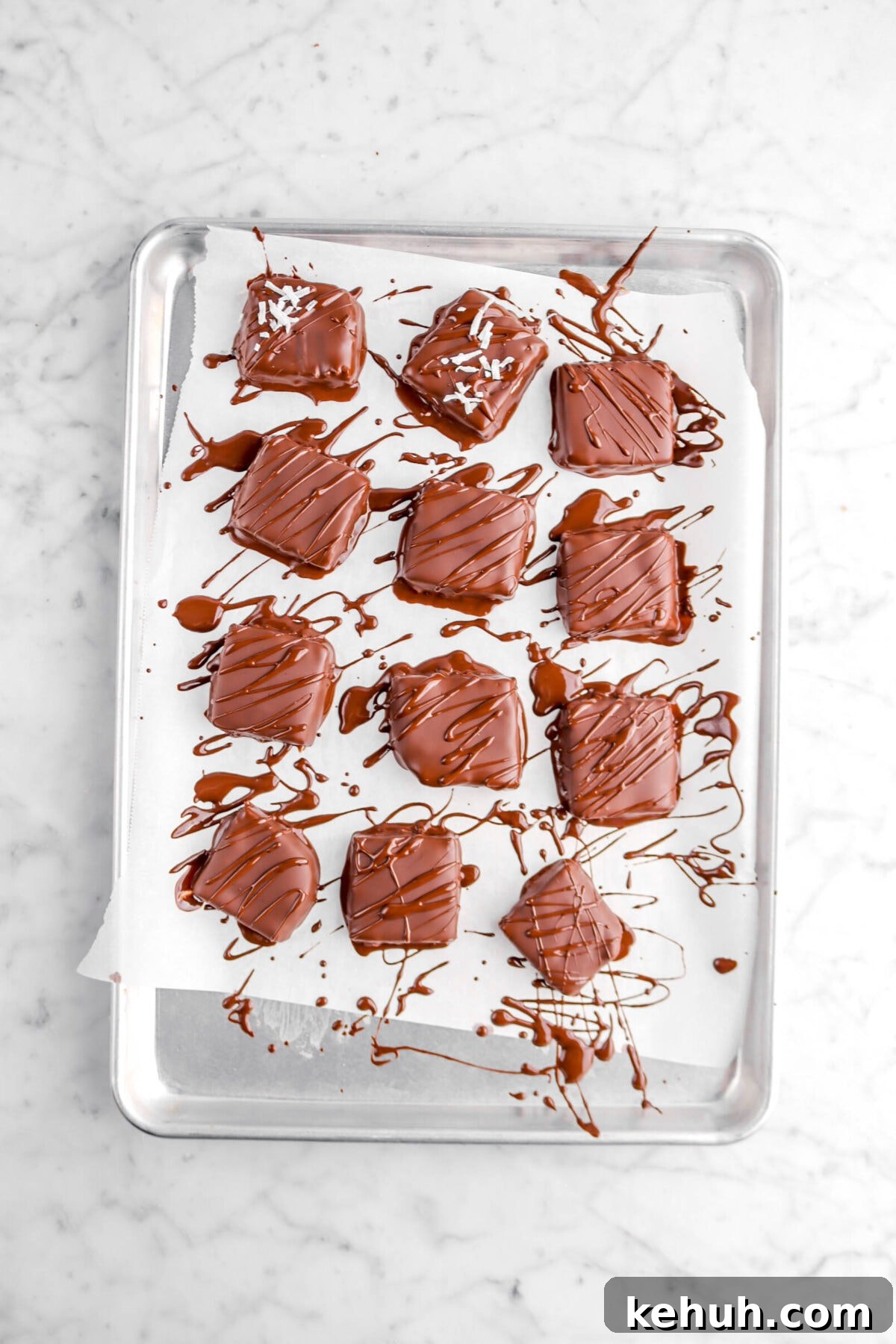 Coconut Cream-Filled Chocolate Truffles: Decadent Homemade Recipe 16 square chocolates with chocolate drizzled over them on parchment lined sheet pan