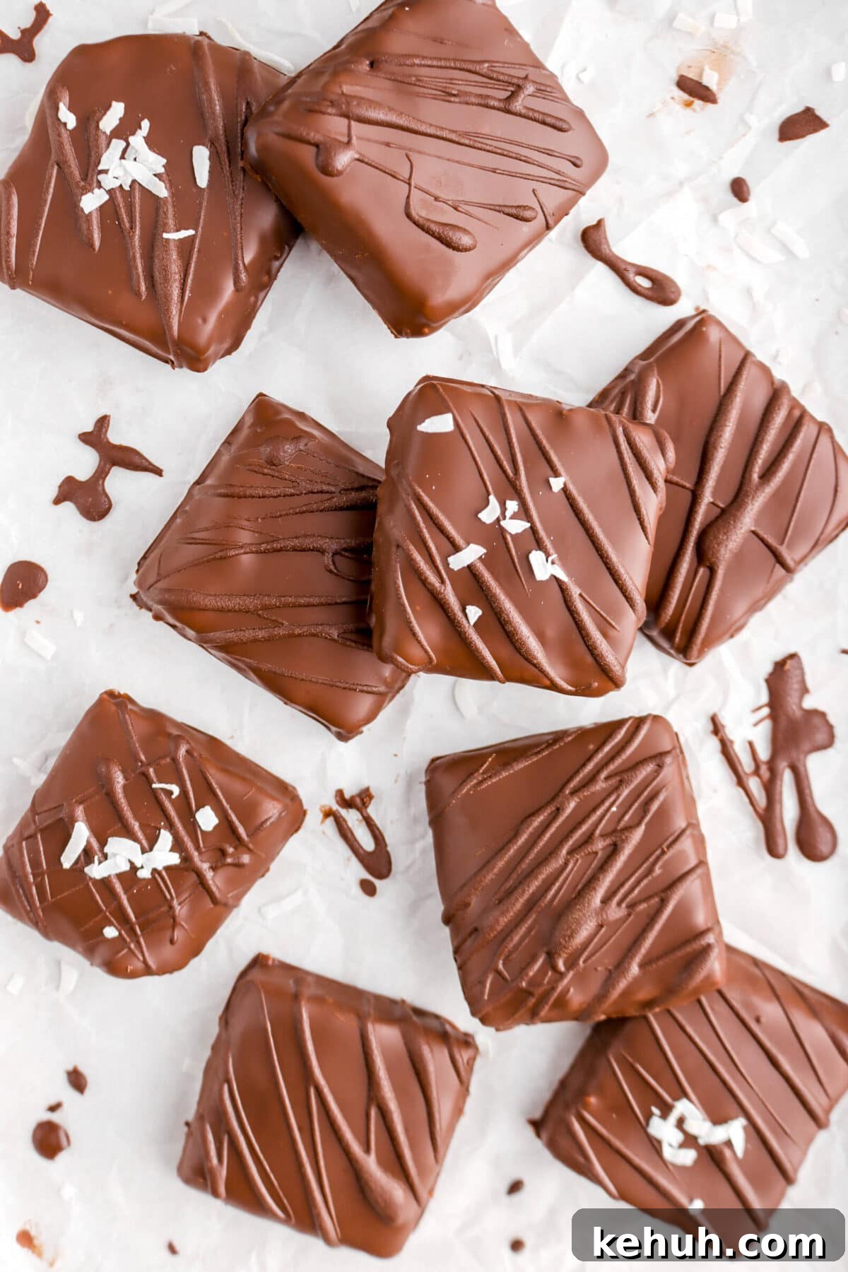 Coconut Cream-Filled Chocolate Truffles: Decadent Homemade Recipe 19 nine square chocolates on crinkled parchment paper with coconut flakes on four of them