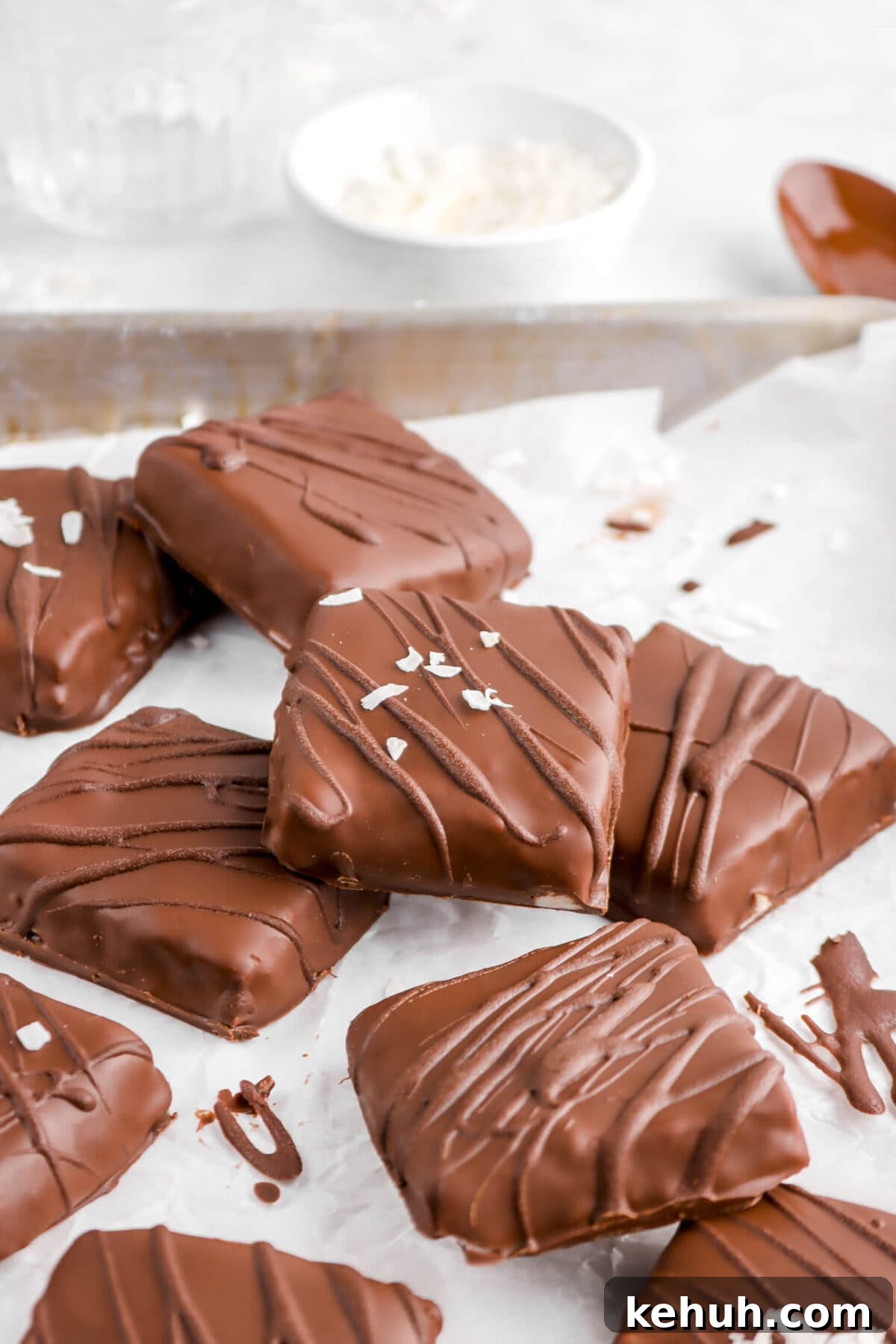 Coconut Cream-Filled Chocolate Truffles: Decadent Homemade Recipe 20 chocolates on parchment paper in sheet pan with bowl of coconut flakes behind