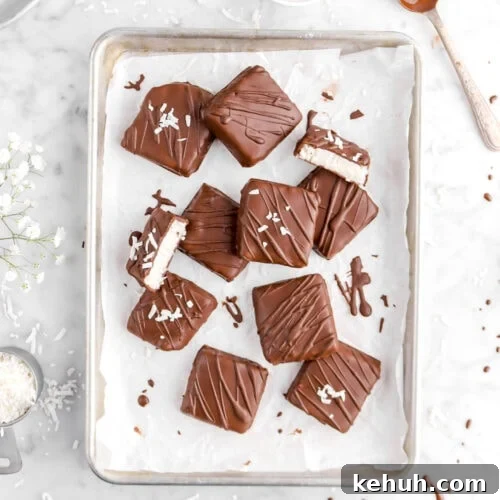 Coconut Cream-Filled Chocolate Truffles: Decadent Homemade Recipe 21 overhead shot of ten coconut filled chocolates with one cut in half, bowls of flaked coconut around, and spoonful of melted chocolate on marble surface