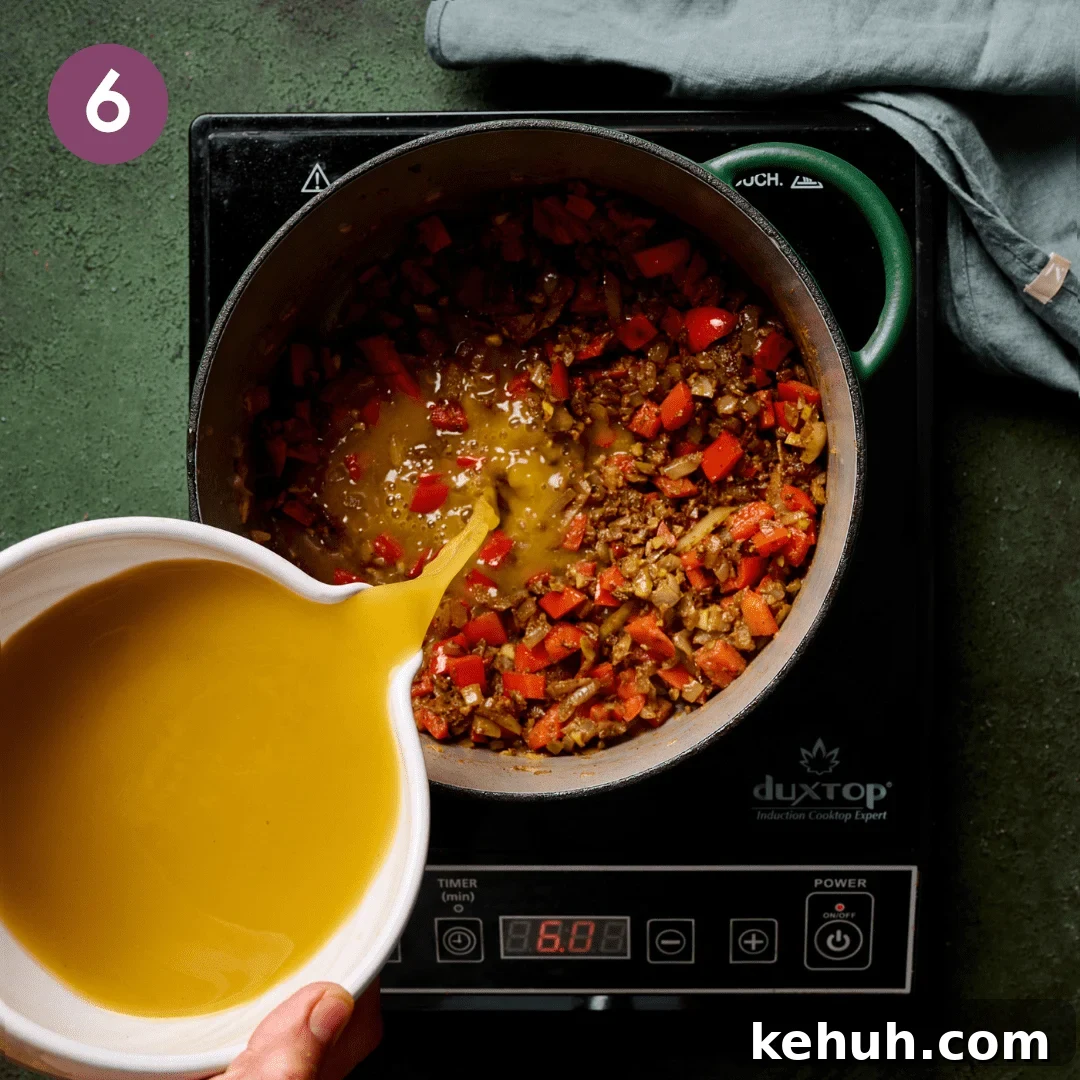 Person pouring vegetable broth into the pot.